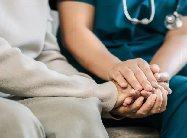 A healthcare worker holding an elderly patient's hand in comfort.