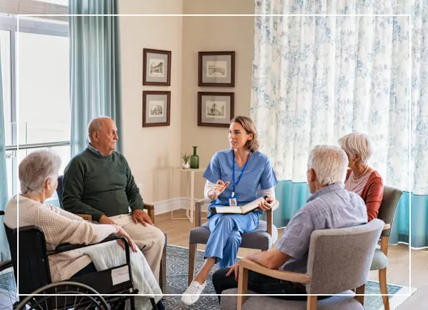 A healthcare professional talking with elderly patients in a cozy room.